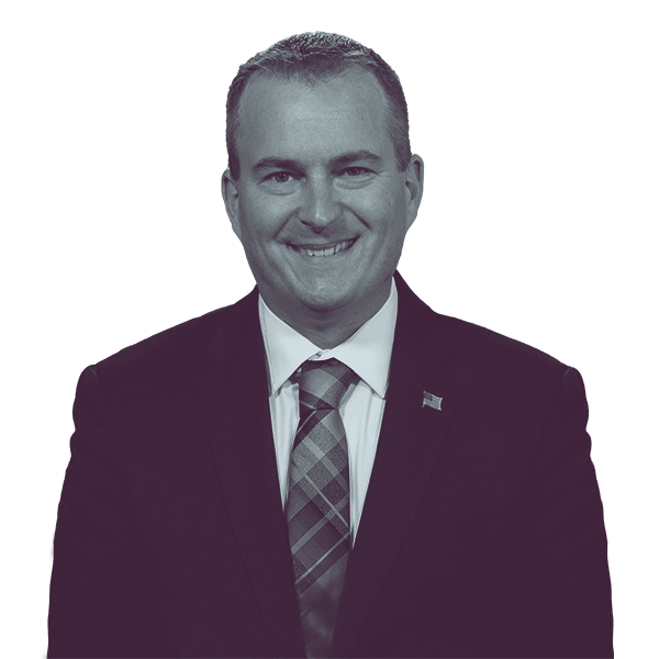 A black and white portrait of Brian Munroe of PA HD-144 from the waist up, smiling and looking into the camera.