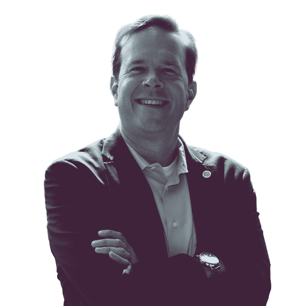 A black and white image of Matt Koleszar of Michigan House district twenty-two from the waist up, smiling and looking into the camera.