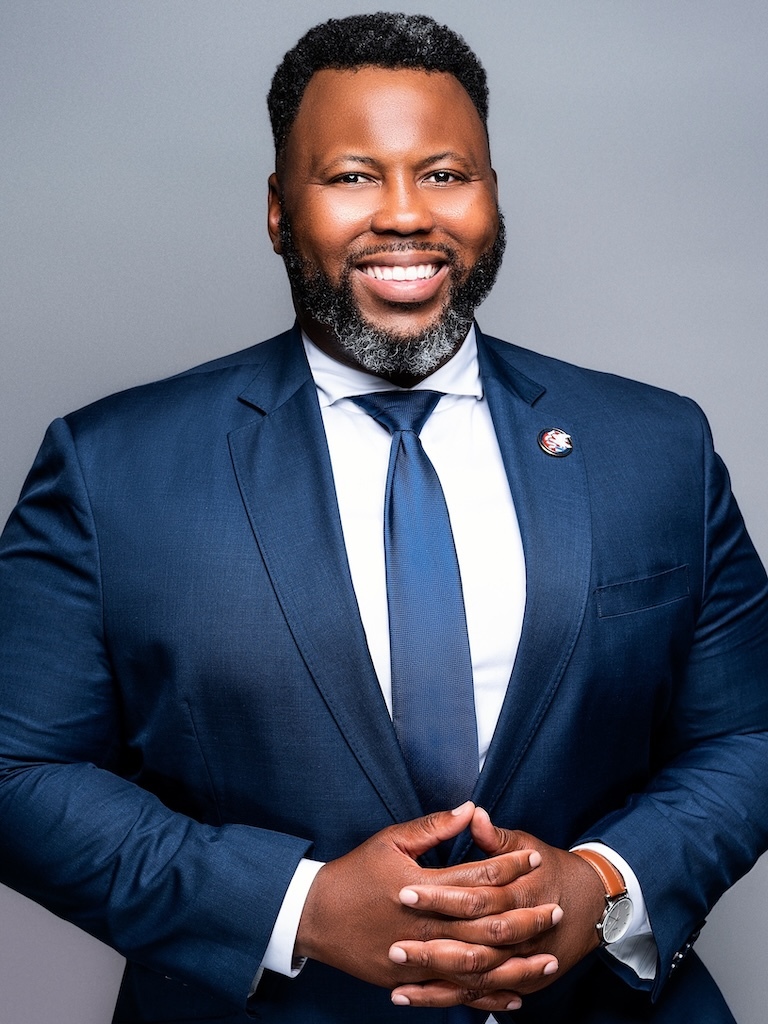 A professional portrait of DLCC Board Secretary and Illinois House Speaker Pro Tempore Kam Buckner.